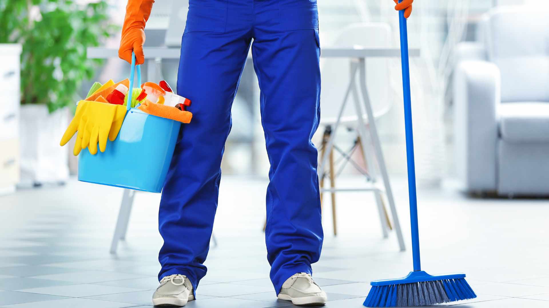 Residential cleaner holding a cleaning caddy in one hand and then a broom in the other