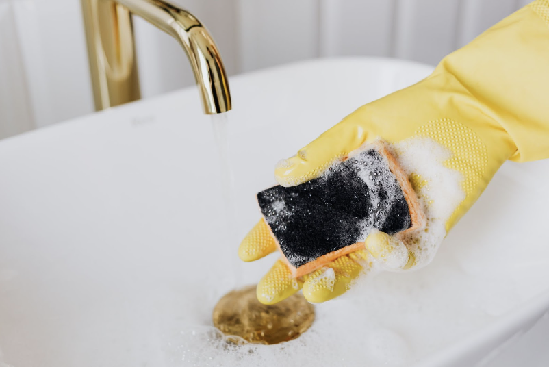Hand holding a soapy sponge while wearing a glove