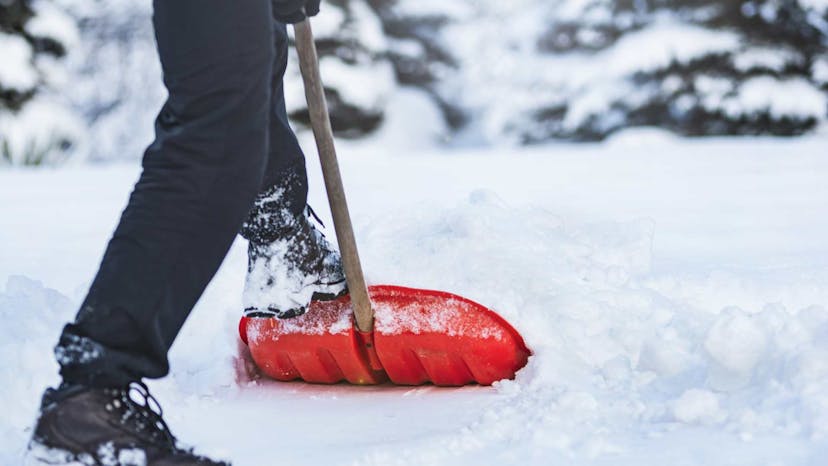 Man shoveling snow with a red shovel
